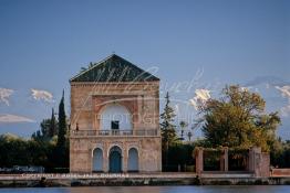 Image du Maroc Professionnelle de  La Ménara est un vaste jardin planté d'oliviers créé au milieu du 12 ème siècle sous le règne de la dynastie Almohade où les visiteurs peuvent s’incliner un moment à l’ombre entre d’innombrables oliviers. Ce pavillon ocre devant les montagnes du Grand Atlas enneigé fait partie des emblèmes de la ville rouge.  Au cœur de ce jardin, un grand bassin au pied d'un pavillon avec son petit toit en forme de pyramide qui peut être à l'origine de son appellation. le Vendredi 19 Décembre 1986. (Photo / Abdeljalil Bounhar) 